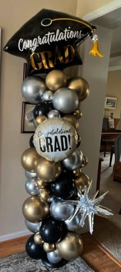 Graduation balloon column in black, gold, and silver with 'Congratulations Grad' foil and silver burst star