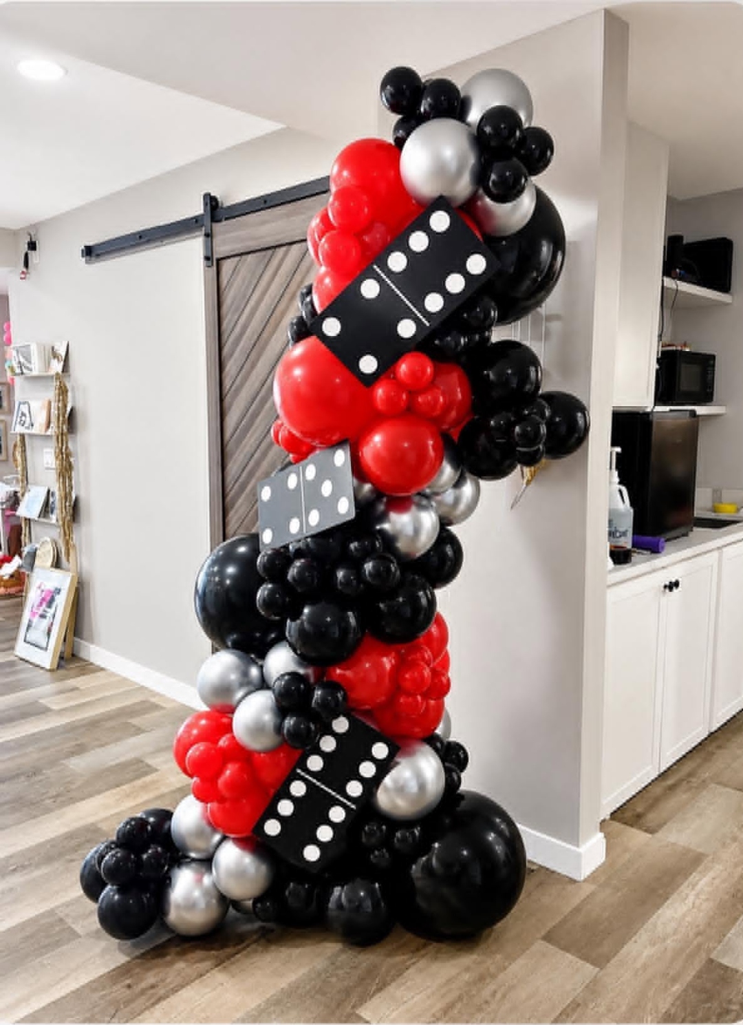 Free-standing balloon column on a stand in red, black, and silver with giant 5-2 and 5-3 domino props for a casino-theme event