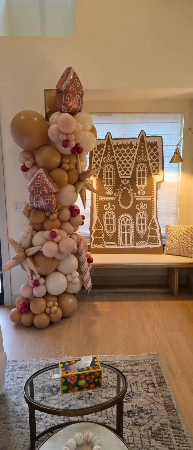 Gingerbread house holiday balloon garland in tan, cream, and white with gingerbread house foils, red berry clusters, candy cane foil, and starburst foil accents