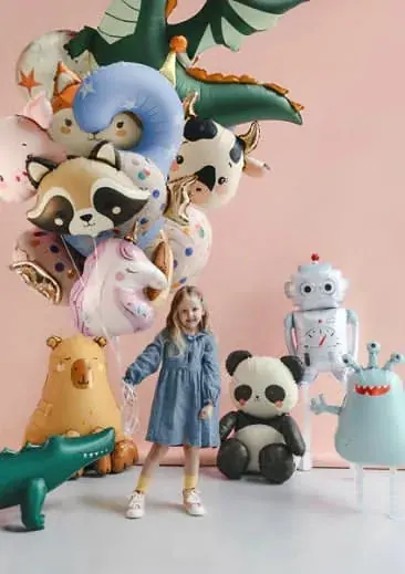 Character mylar balloon bouquet featuring dragon, raccoon, cow, unicorn, panda, robot, monster, and crocodile shapes around a young child