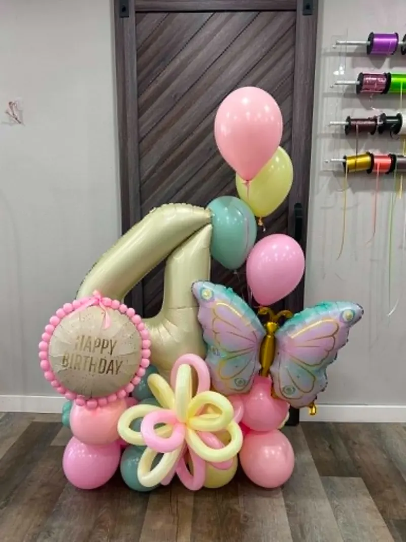 Pastel birthday balloon stack with cream number one, iridescent butterfly foil, pink Happy Birthday round, and pastel balloon flower