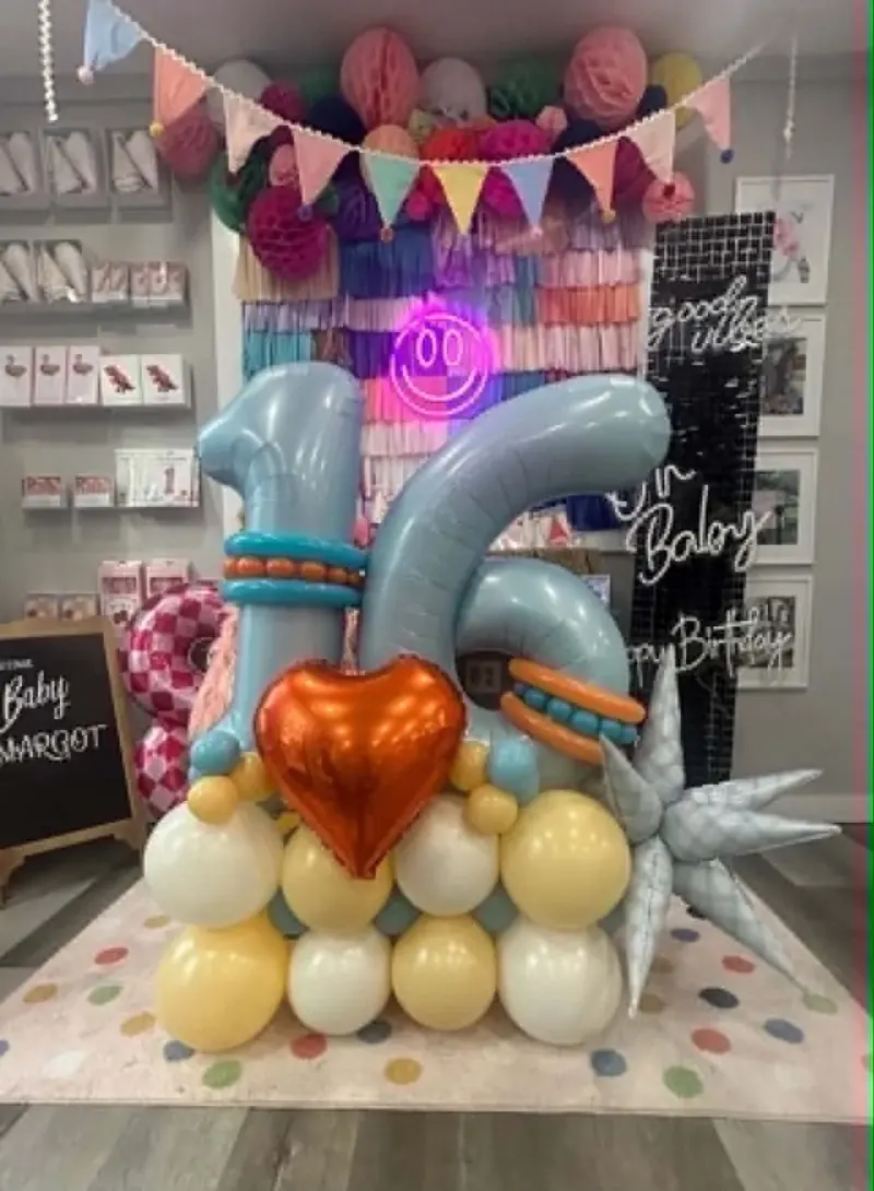 Sweet 16 balloon stack with pastel blue number balloons, orange foil heart, and yellow and white balloon base