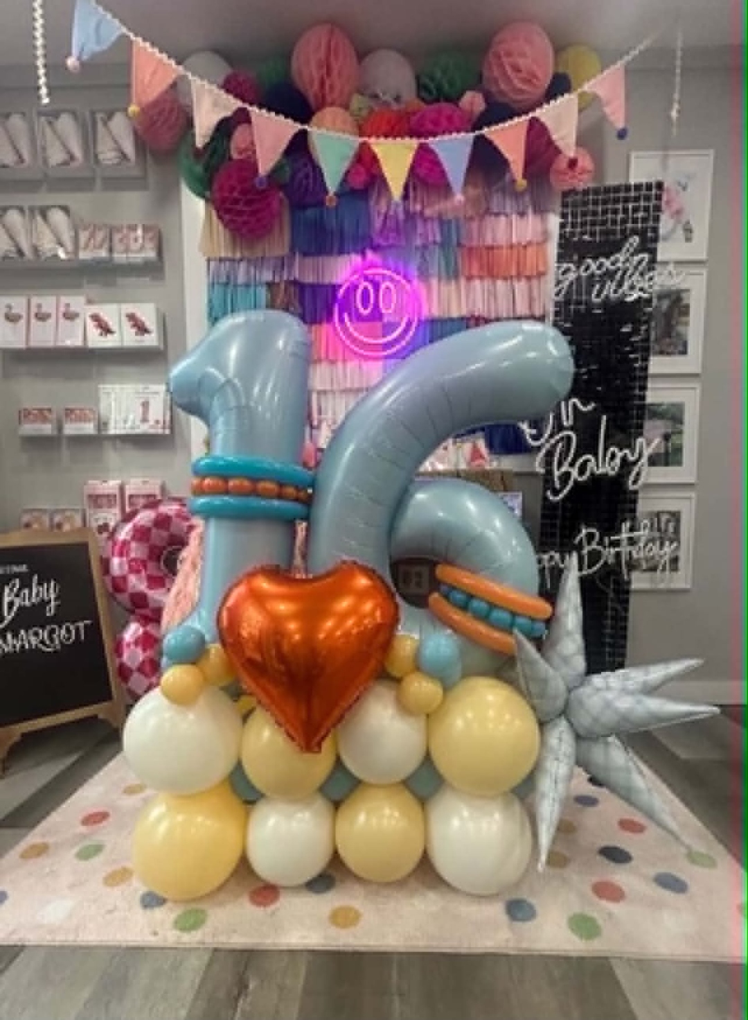 Sweet 16 balloon stack with pastel blue number balloons, orange foil heart, and yellow and white balloon base