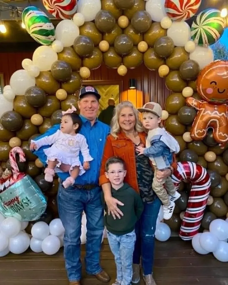Holiday balloon arch wall in brown, tan, and cream with peppermint candy foils, gingerbread man foil, candy cane foil, and Happy Days mug foil framing a family portrait