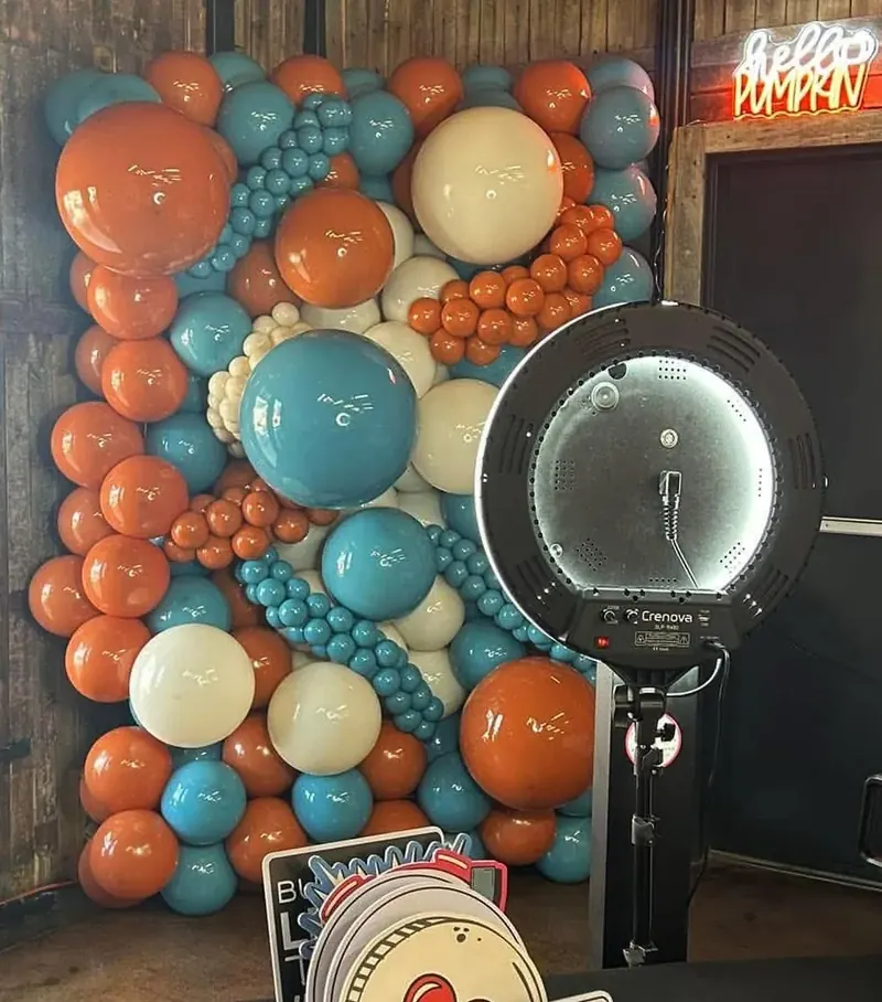 Balloon wall in burnt orange, teal, and cream with mixed sizes — photo booth backdrop