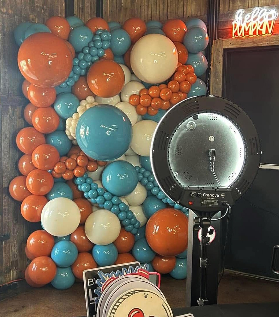 Balloon wall in burnt orange, teal, and cream with mixed sizes — photo booth backdrop